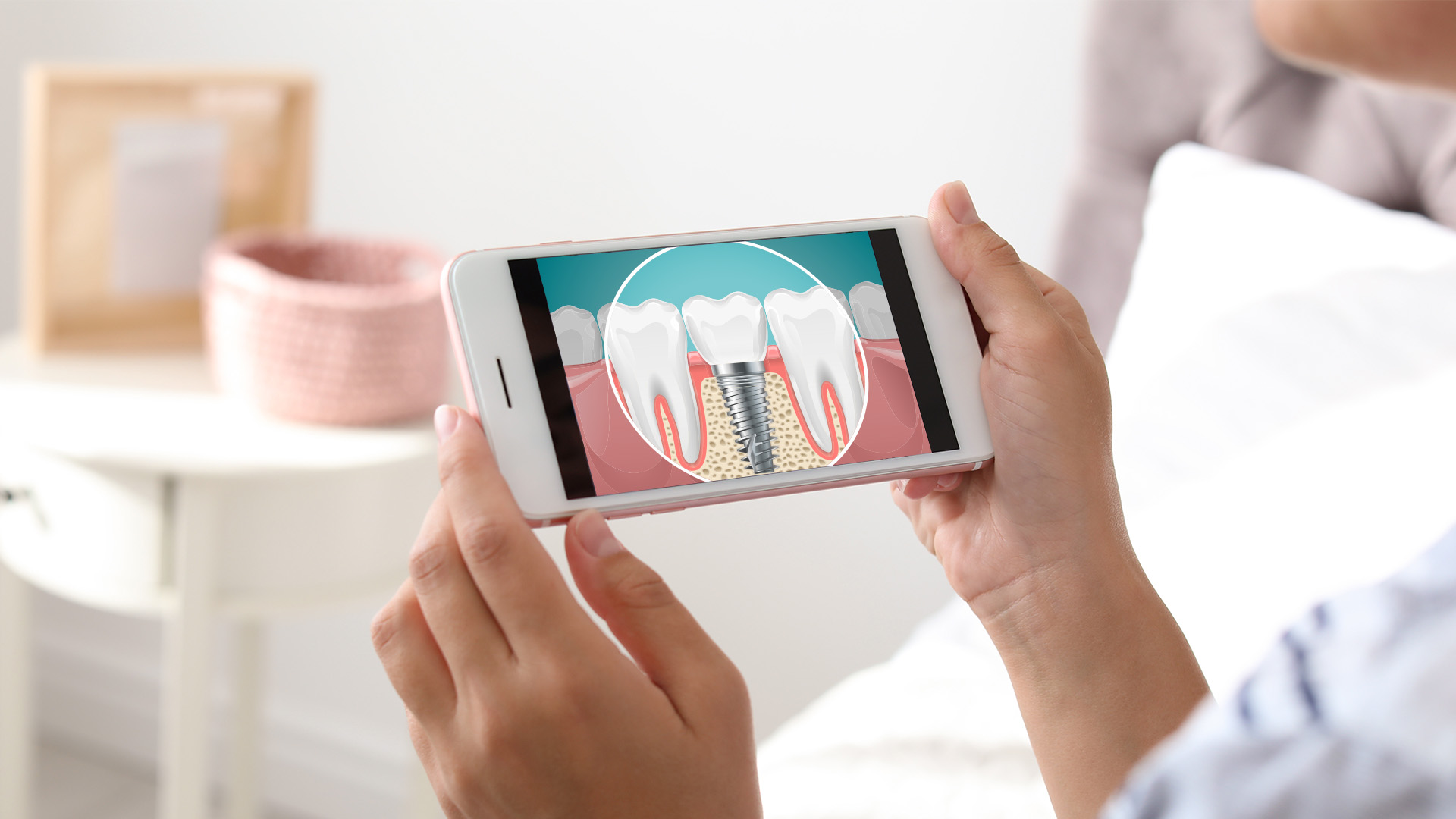 A person holding a smartphone displaying an image of a tooth with a magnified view of its structure and gums, suggesting dental health or oral care education.