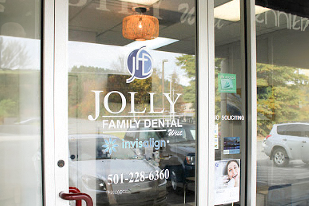 The image shows a storefront with a sign that reads  Jolly Family Dental  and a phone number below it.