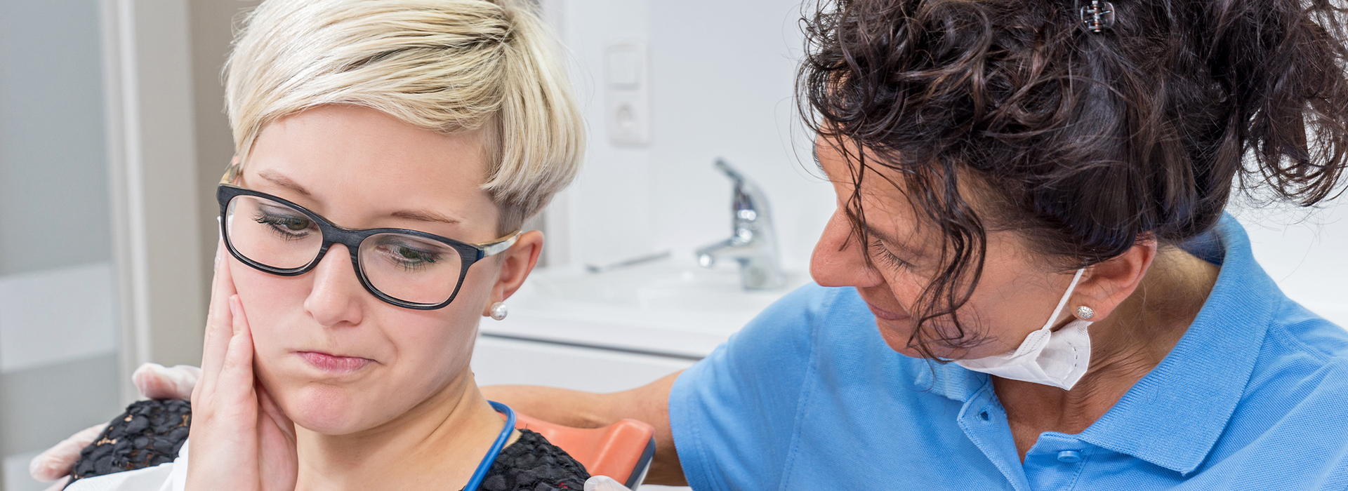 Woman getting facial treatment at beauty salon by professional wearing blue shirt.