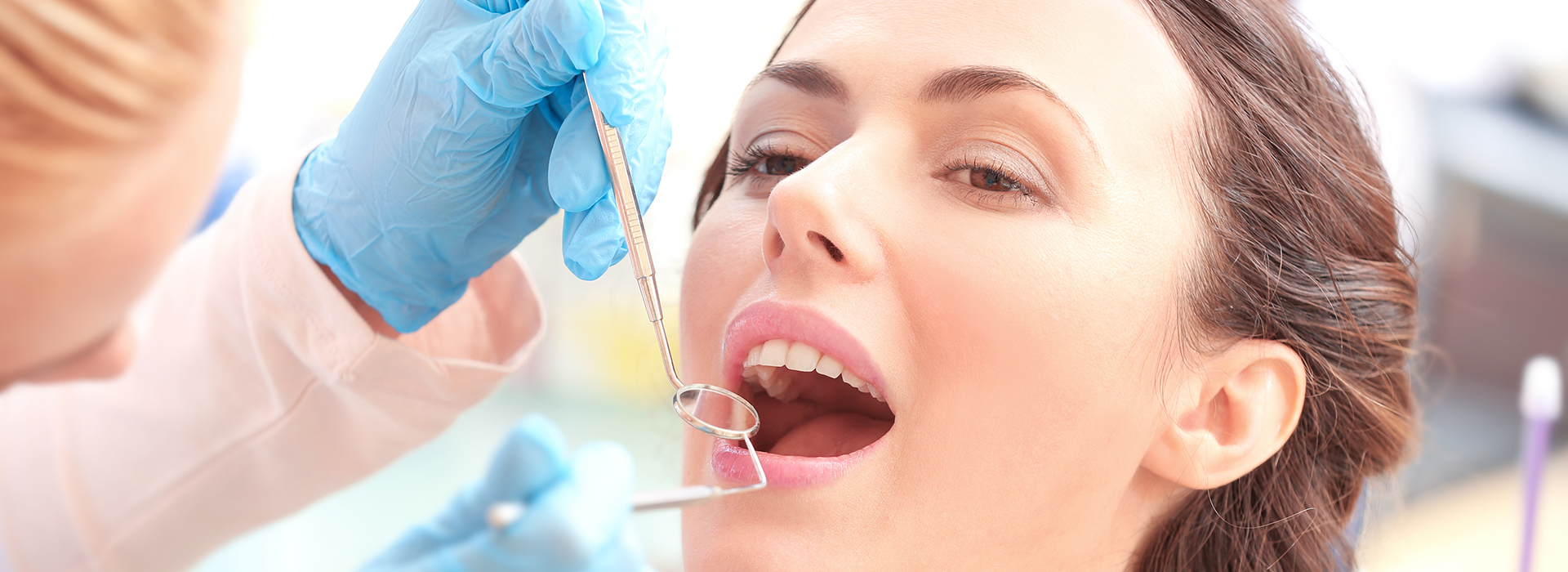 A dental hygienist is using a drill on a patient s teeth during a dental procedure.