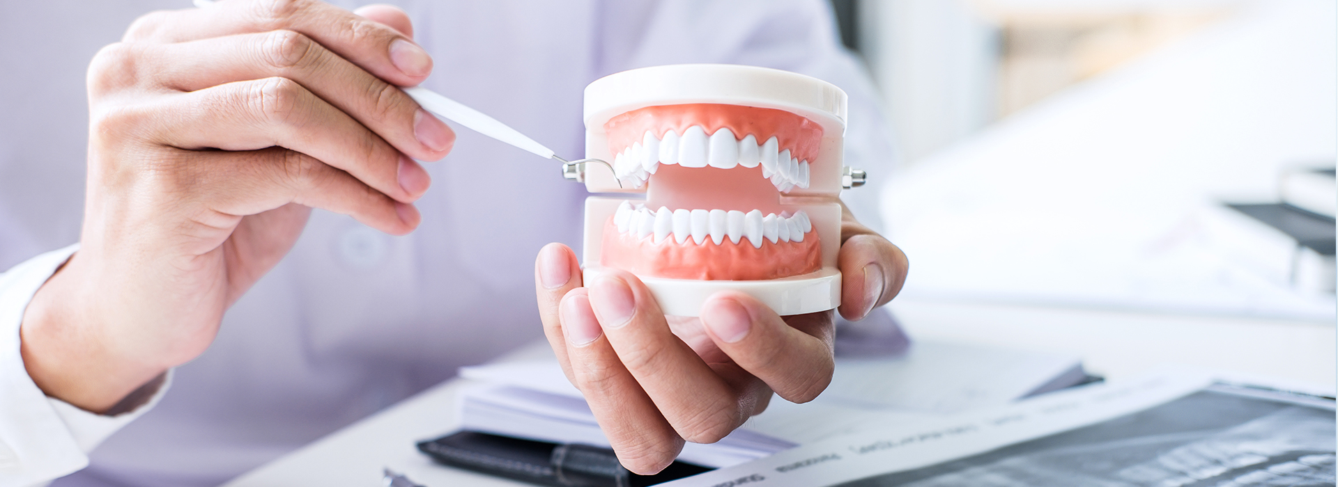 The image depicts a person s hand holding a toothbrush with a red and white toothpaste tube, while another hand holds a cup of water, suggesting dental hygiene practices.