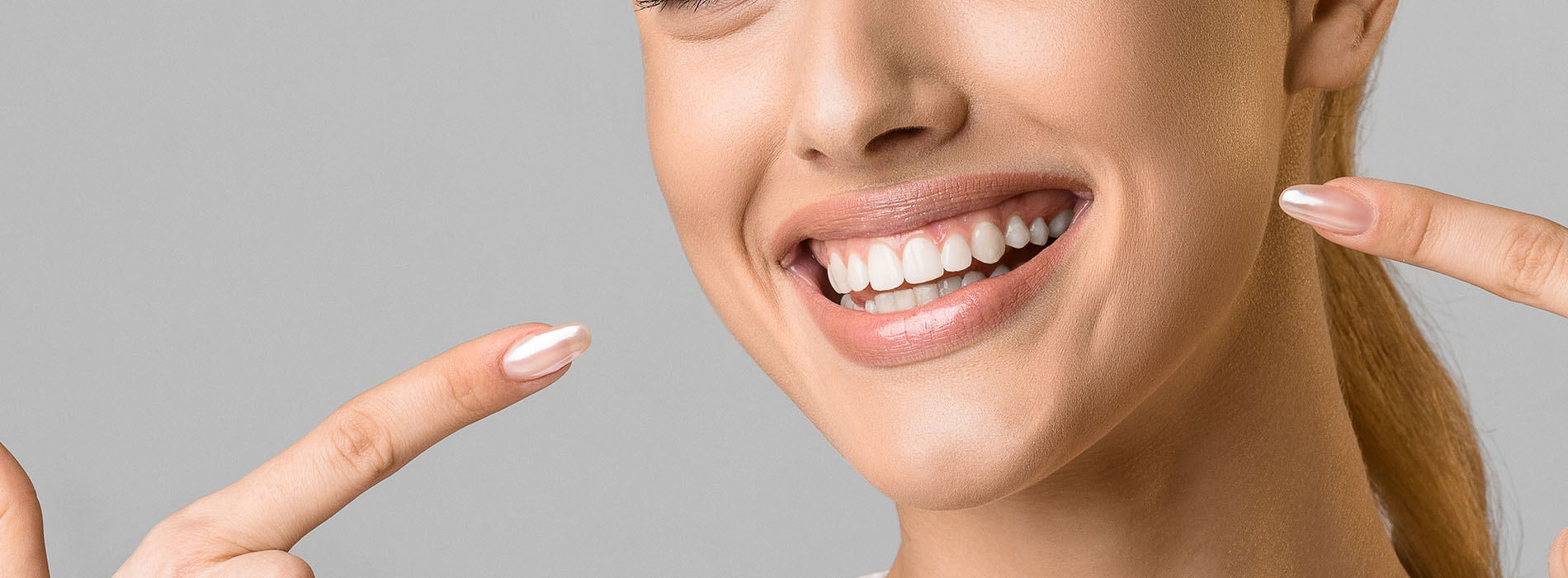 The image shows a smiling woman with her fingers held up to her face, possibly indicating a gesture of joy or approval.