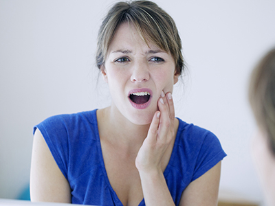 A woman with a surprised expression, holding her hand to her mouth, appears to be reacting to something out of frame.