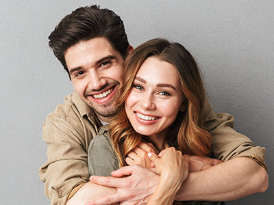 A young couple embracing each other with smiles on their faces.